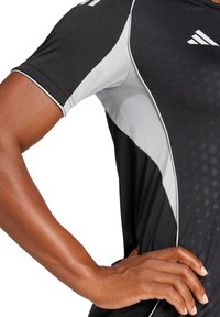 Heren sportshirt met een zwarte romp, grijze zijkanten, witte accenten en een gestructureerd patroon. Gemaakt van vochtregulerende stof.