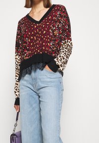 Maglione lavorato a maglia con scollatura a V, caratterizzato da un design floreale e a stampa leopardata in bordeaux, nero e crema. Orlo in pizzo nero e maniche lunghe.
