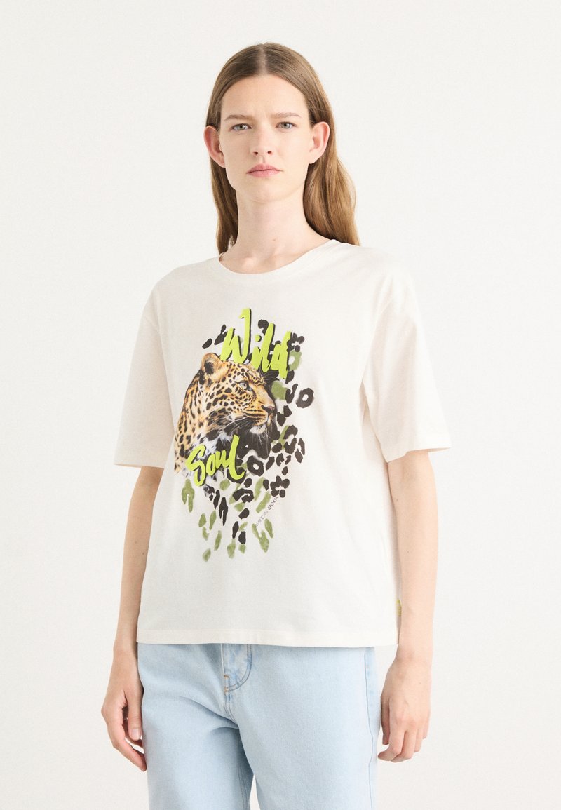 Hvit bomull T-skjorte med et leopardgrafikk og teksten "Wild Soul" i grønt, med svarte flekker og subtile grønne aksenter i designet.