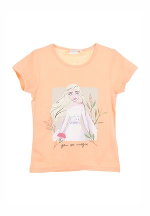 Perzikkleurig t-shirt met korte mouwen van katoen, met een grafisch ontwerp van een karakter omringd door bladeren en bloemen, met de tekst "je bent magie."