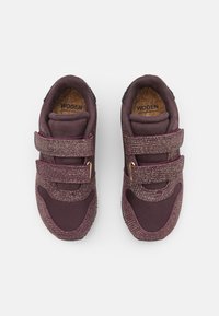 Sneaker color bordeaux con una parte superiore strutturata, dotate di due cinturini in velcro, suola interna in sughero e dettagli in rete per traspirabilità e comfort.