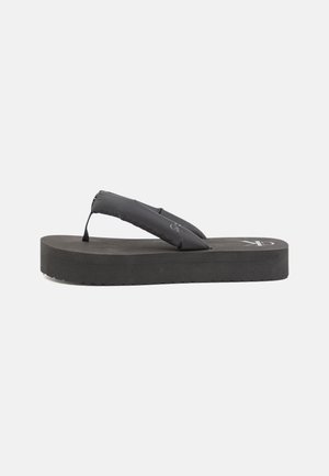 Black flip flop with a padded strap, thick rubber sole, and textured footbed. Features a logo on the top and a slightly elevated design.