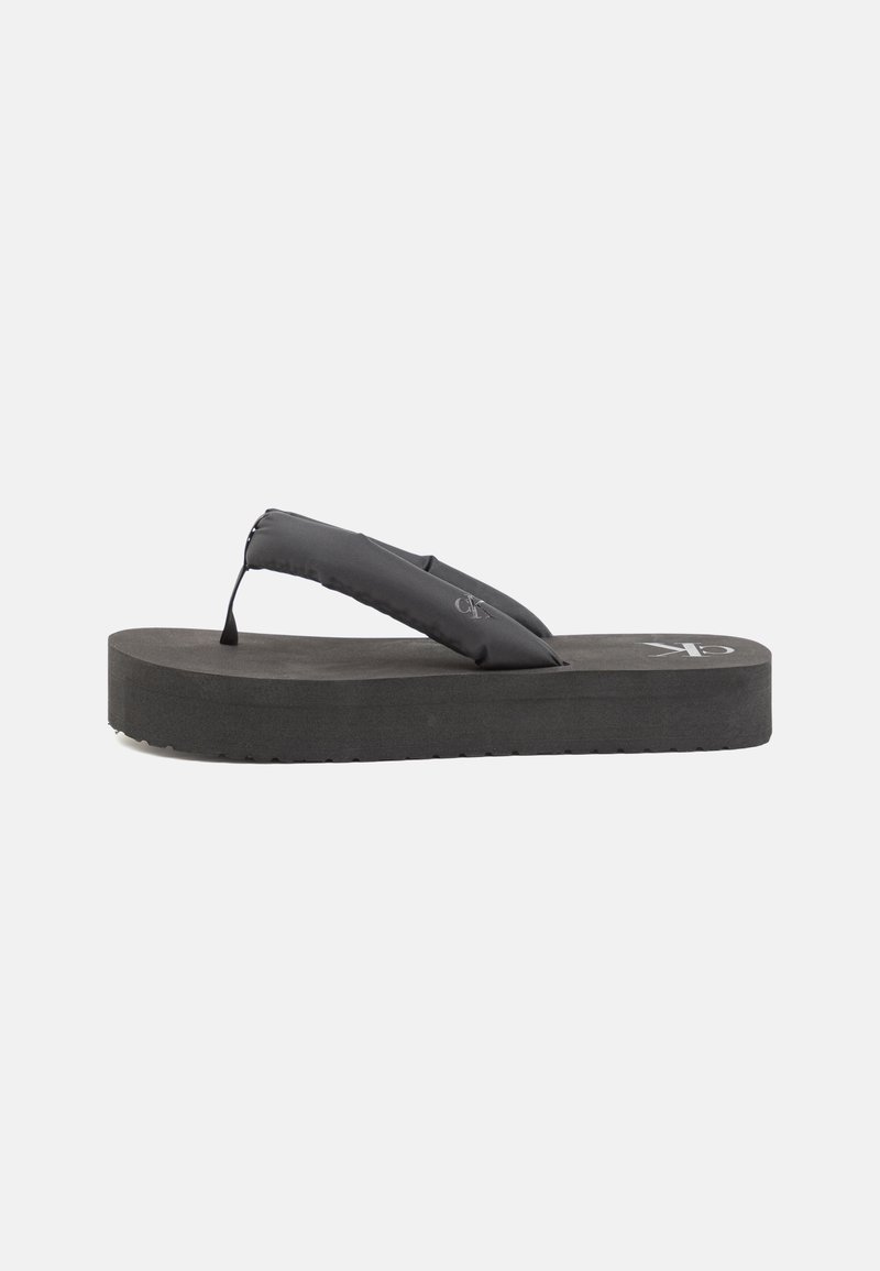 Svart flip-flop med vadderad rem, tjock gummisula och texturerad fotbädd. Har en logotyp på ovansidan och en något upphöjd design.