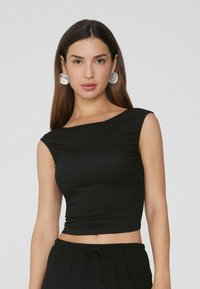Top nero a maniche corte con design aderente, scollatura ampia e taglio corto. Realizzato in un tessuto morbido e elasticizzato.