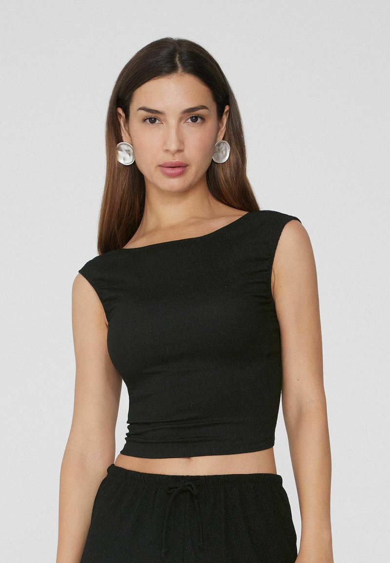 Top nero a maniche corte con design aderente, scollatura ampia e taglio corto. Realizzato in un tessuto morbido e elasticizzato.