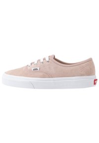 Sneaker basse in suede beige di Vans con lacci bianchi e suola in gomma bianca, dotata di un piccolo etichetta con il logo Vans sul lato.