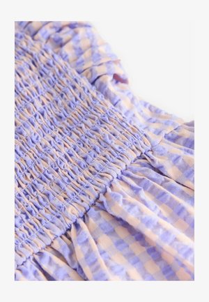 Lila och persika rutigt tyg har en smockad textur med rynkade detaljer och volangkanter. Lättvikts bomullsmaterial.