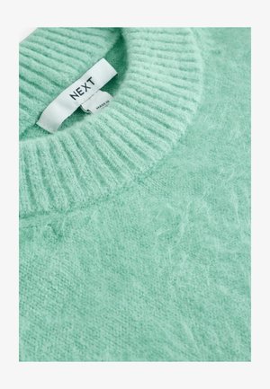 Mátově zelený svetr s žebrovaným kulatým výstřihem a měkkou, nadýchanou texturou, s viditelnou štítkovou značkou uvnitř límce.