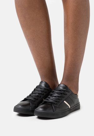 Black leather sneakers with lace-up design, featuring a subtle side stripe detail and textured rubber sole. Smooth finish on upper.