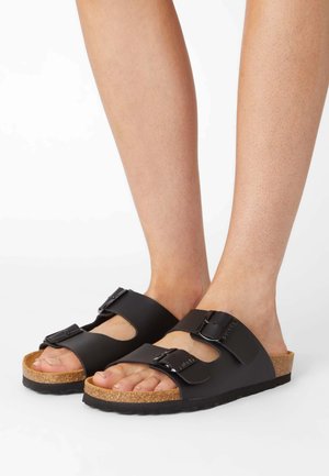 Sorte slip-on sandaler med korksål, justerbare remme og spænde detaljer. Glat overmateriale og tekstureret sål for komfort.