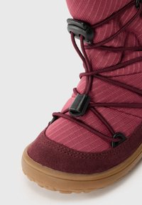 Waterdichte boot met een bordeauxrood textielen bovenwerk met ribbeltextuur, elastisch vetersysteem en een bruine rubberen zool.
