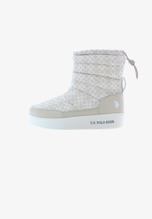 Beige nilkkurit, joissa on tikattu päällinen valkoisella kuviolla, valkoinen pohja ja sivulogo. Sisältää vetoketjun ja säädettävän narun.