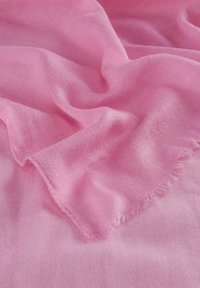 Tissu rose, léger et aérien, avec une finition texturée et des bords effilochés, présenté en douces plis et drapés.