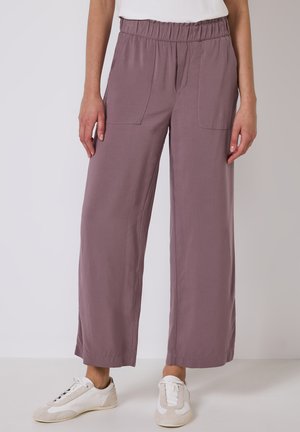 Lavendelkleurige wijde broek met een elastische tailleband, twee front pockets en een soepele stofstructuur, gecombineerd met witte sneakers.