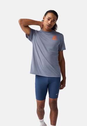 Gray athletic t-shirt with short sleeves and an orange logo, paired with blue shorts. The fabric appears lightweight and smooth.