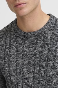Szary sweter dzianinowy z teksturowanym wzorem w warkocze, okrągłym dekoltem i ściągaczami. Materiał wydaje się gruby i ma miękką fakturę.