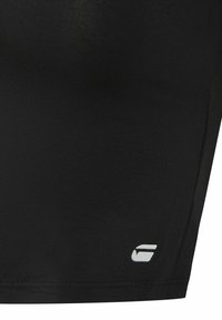 Black athletic shorts made from stretchy fabric, featuring a white logo on the lower hem and smooth, textured surface.