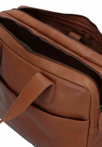Braune Leder-Umhängetasche mit zwei Fächern, Reißverschlussverschlüssen und einer Fronttasche. Glatte Textur mit sichtbaren Nähten und Branding.