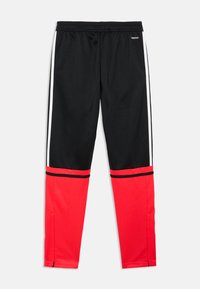 Schwarze Sporthose mit roten unteren Abschnitten, weißen Seitenstreifen, elastischem Bund und glatter Textur. Verfügt über einen schwarzen Rand nahe dem Saum.