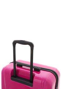 Pink hard-shell suitcase with a glossy finish, features a textured black handle and zipper. Compact design with a rectangular shape, minimal accents.