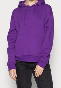 Felpa con cappuccio viola realizzata in tessuto morbido, dotata di tasca a marsupio, cordini e polsini e inferriata a coste. Design semplice, senza motivi.