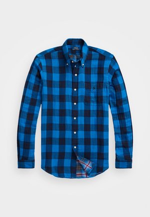 Blau-schwarz karierte Langarm-Hemd mit Knöpfen und Tasche. Hat ein kariertes Muster im Kragen und Saum. Aus Baumwollmaterial.