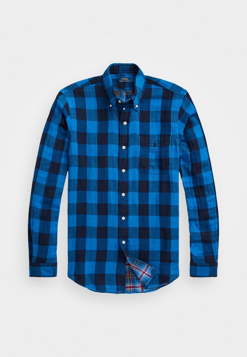Camisa de botones de manga larga a cuadros azul y negro con un bolsillo. Presenta un patrón de cuadros dentro del cuello y el dobladillo. Material de algodón.