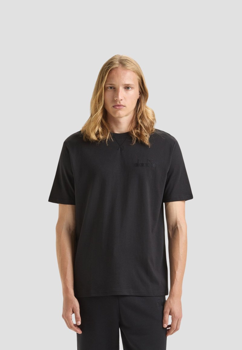 T-shirt in cotone nero con scollatura rotonda e maniche corte. Presenta un logo nero discreto sul petto. Design semplice e dritto.