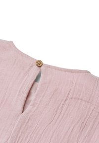 Tela rosa claro con superficie texturizada, mostrando un primer plano de un botón redondo de madera que abotona un escote con abertura en forma de ojo de cerradura.