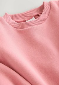 Helles rosa Sweatshirt mit geripptem Rundhalsausschnitt und glatter Stoffoberfläche, flach auf einer hellen Fläche ausgelegt.