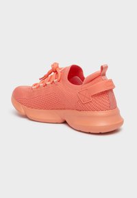 Chaussure de sport corail avec empeigne en mesh, bout arrondi et semelle rembourrée. Présente des détails texturés et une languette de renfort au talon.
