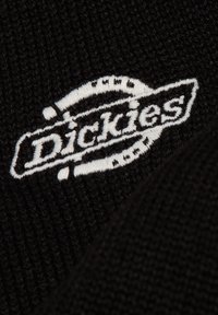 Sort strikket beanie med hvidt broderet "Dickies" logo. Har struktureret mønster og glat overflade. Kompakt og tætsiddende pasform.