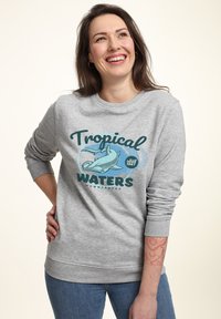 Šedá mikina s grafikou "Tropické vody" znázorňující žraloka hammerhead. Ribe výstřih a lem. Stylizováno s modrými džíny.