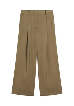 Femme portant un caraco en satin marron foncé, un pantalon marron ample taille haute avec une grande boucle de ceinture, et des sandales couleur nude marchant à l'intérieur.