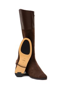 Braune Wildleder-Stiefel bis zum Knie mit einem glatten, dunkelbraunen Lederoberteil, spitzem Zehenbereich und flacher Sohle. Die Außensohle verfügt über ein beiges Pad und Branding-Details.
