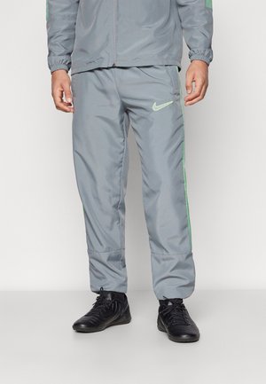 Pantalones de chándal grises de Nike con corte ajustado, que cuentan con franjas laterales y logo en verde neón. Hechos de un material suave y ligero.