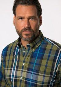 Camisa de cuadros para hombre en verde, azul y marítimo. Presenta un cuello abotonado, patrones de cuadros en contraste y dos bolsillos en el pecho. Material de algodón.