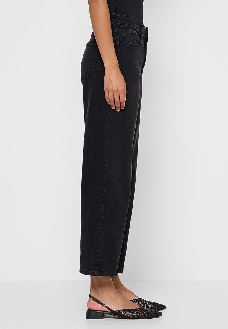 Hoge zwarte denim jeans met een rechte pijp, voorzien van voorzakken en subtiele stiksels. Gepaard met zwarte gepatterneerde flats.