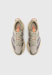 Ζευγάρι μπεζ και γκρι παπούτσια για τρέξιμο με πορτοκαλί λεπτομέρειες, τα κορδόνια δεμένα, σε θέα από πάνω σε λευκό φόντο.