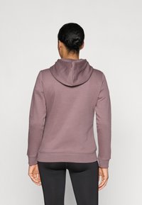 Kapučiņa džemperis mauve audumā, ar ribotām aprocēm un apakšmalu. Gluda tekstūra ar aizmugures skatu, kas rāda brīvu piegriezumu un kapuces detaļas.