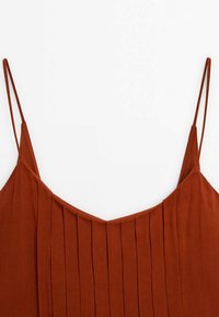 Robe sans manches couleur rouille avec fines bretelles spaghetti et plis verticaux sur le devant du corsage, sur fond blanc.