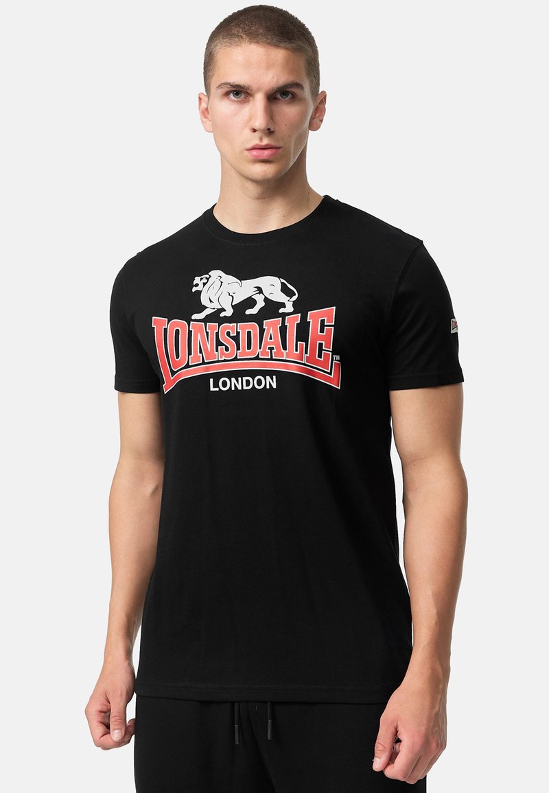 Zwarte katoenen T-shirt met een witte leeuwafbeelding en rode tekst "Lonsdale London". Korte mouwen en een ronde halslijn.