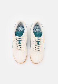Sneakers bianchi con dettagli turchesi, tessuto testurizzato e suola in gomma. Presentano lacci rotondi e una soletta decorata.