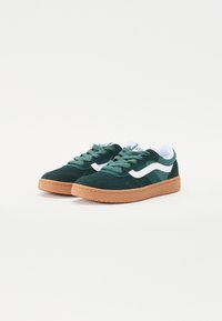 Sapatilhas verdes de camurça com detalhes brancos e sola de borracha bege. Apresentam um design com atacadores, colarinho acolchoado e superfície texturizada.