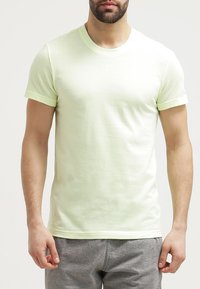Camiseta de manga corta verde claro con un patrón de tela texturizada, presenta un cuello redondo y un dobladillo recto.