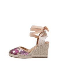 Espadrille de cuña con suela de yute trenzado, adornada con lentejuelas moradas y doradas en la puntera, que cuenta con un suave lazo de cinta beige alrededor del tobillo.