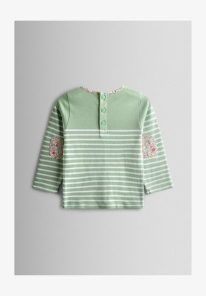 Heleroheline triiksärk valgete triipudega, kaeluses lilleline ääris ja mustrilised küünarnukikatted. Tagaküljel neli nähtavat nööpi.