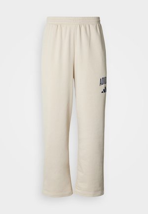 Pantaloni de trening bej cu talie elastică, având un logo „ADIDAS” imprimat în albastru închis și un design cu trei dungi pe lateral. Textură moale.