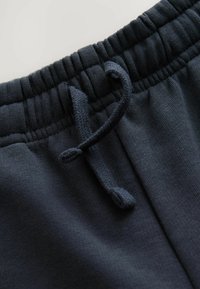 Pantalons de jogging bleu marine foncé avec une texture douce, une taille élastique et un cordon ajustable pour le confort et un bon maintien.
