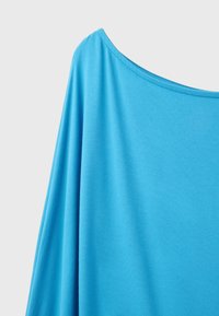 Bright blue fabric with a wide boat neckline and loose draping on one shoulder against a plain light background.